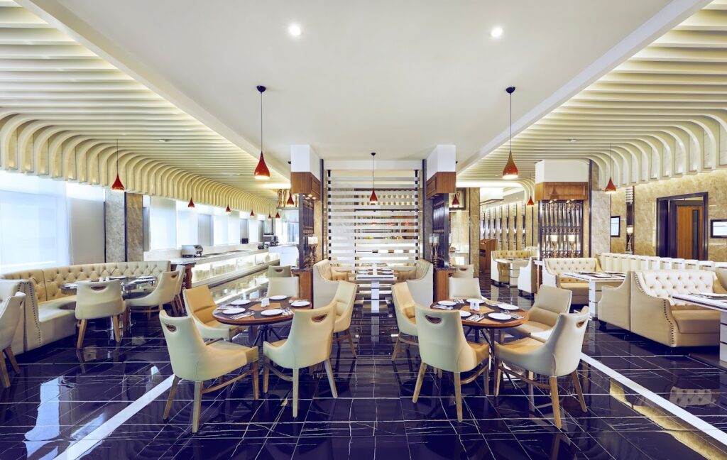 A stylish dining area at Royale, Mercure Singapore Bugis, featuring elegant chandeliers, plush seating, and a warm, inviting ambiance.